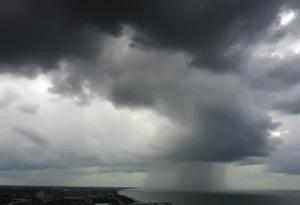 A view of Jacksonville's skyline under dark storm clouds with rain beginning to fall